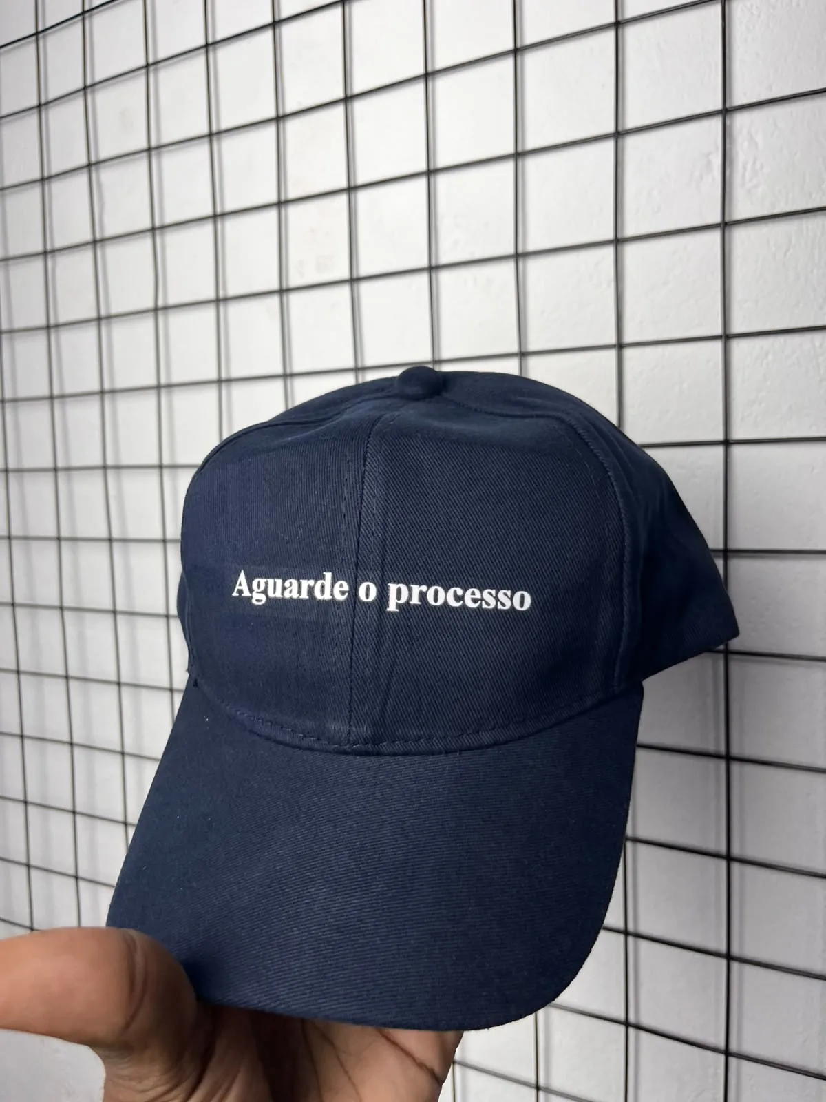 Boné azul-marinho com a frase Aguarde o processo bordada